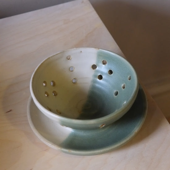 Green ceramic strainer on a wooden surface