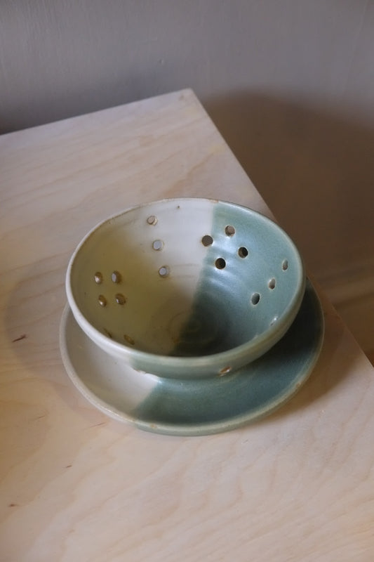 Green ceramic strainer on a wooden surface