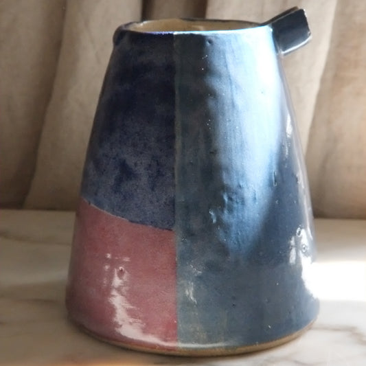 Ceramic pitcher with two-tone design on a neutral background