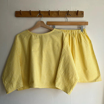 Yellow checkered top and shorts on hangers against a white wall