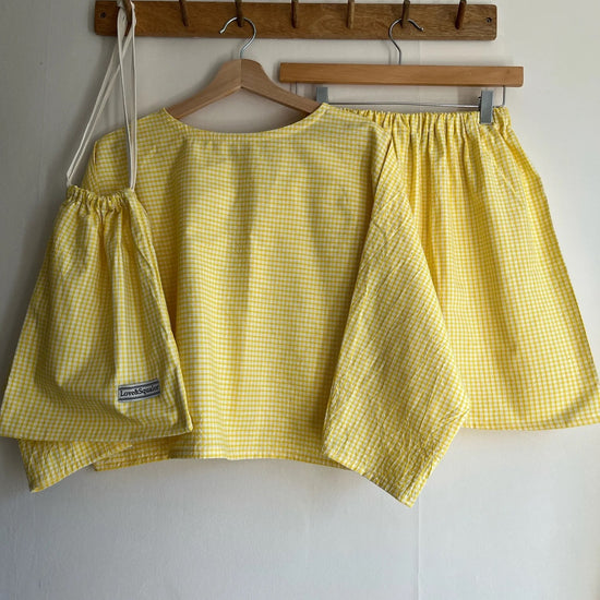 Yellow checkered top and shorts on hangers against a white wall