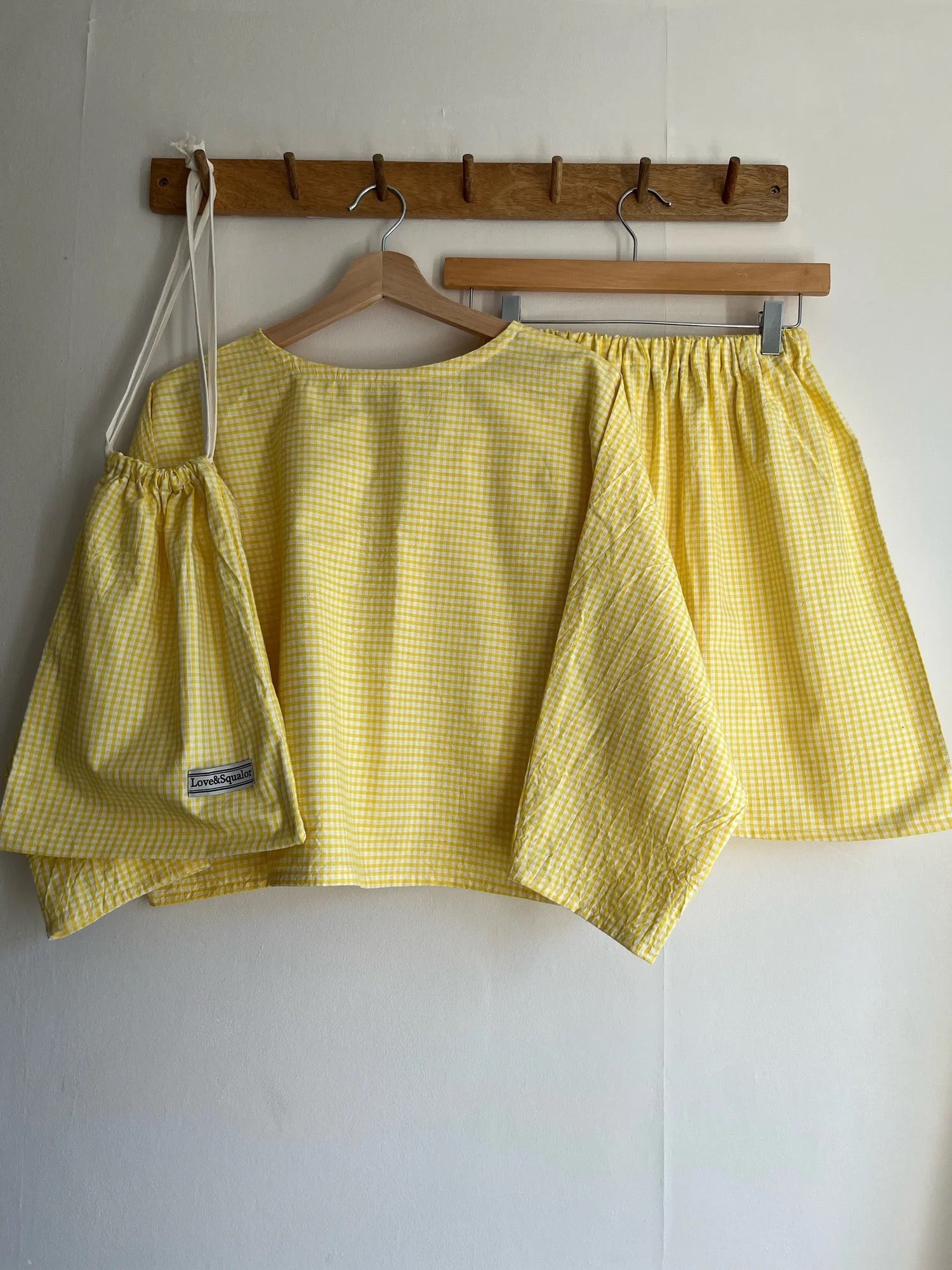 Yellow checkered top and shorts on hangers against a white wall