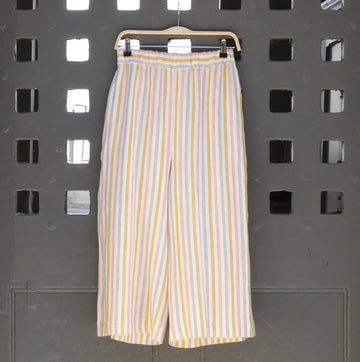 Photo of striped wide leg trousers in pastel colours hanging on a grey door