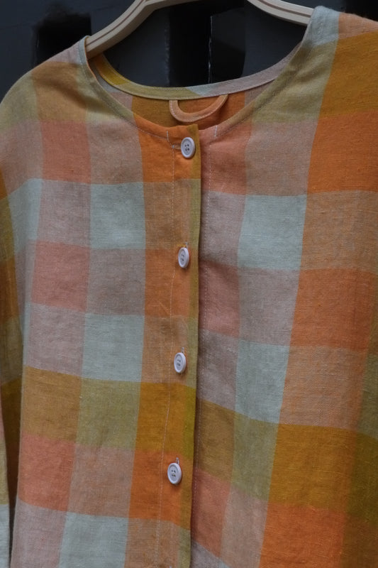 close up photo of a checked collarless shirt with white buttons