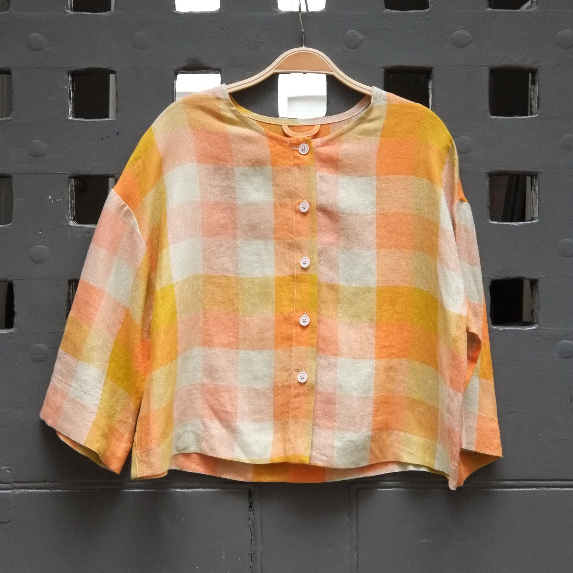 photo of a yellow and orange checked shirt with button front on a grey door 