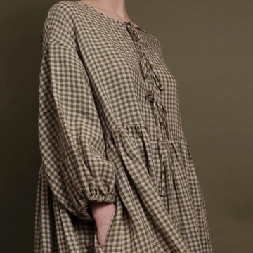 close up of gingham dress with ties at the front and an elasticated sleeve in pink and olive fabric