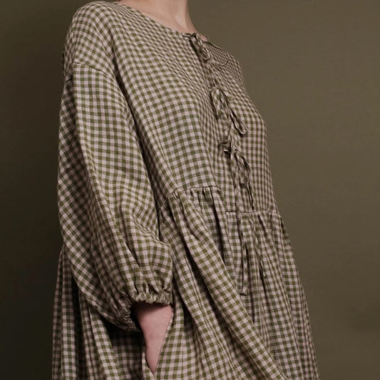 close up of gingham dress with ties at the front and an elasticated sleeve in pink and olive fabric