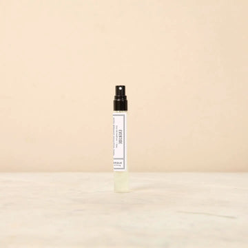 Small spray bottle with a white label on a beige background