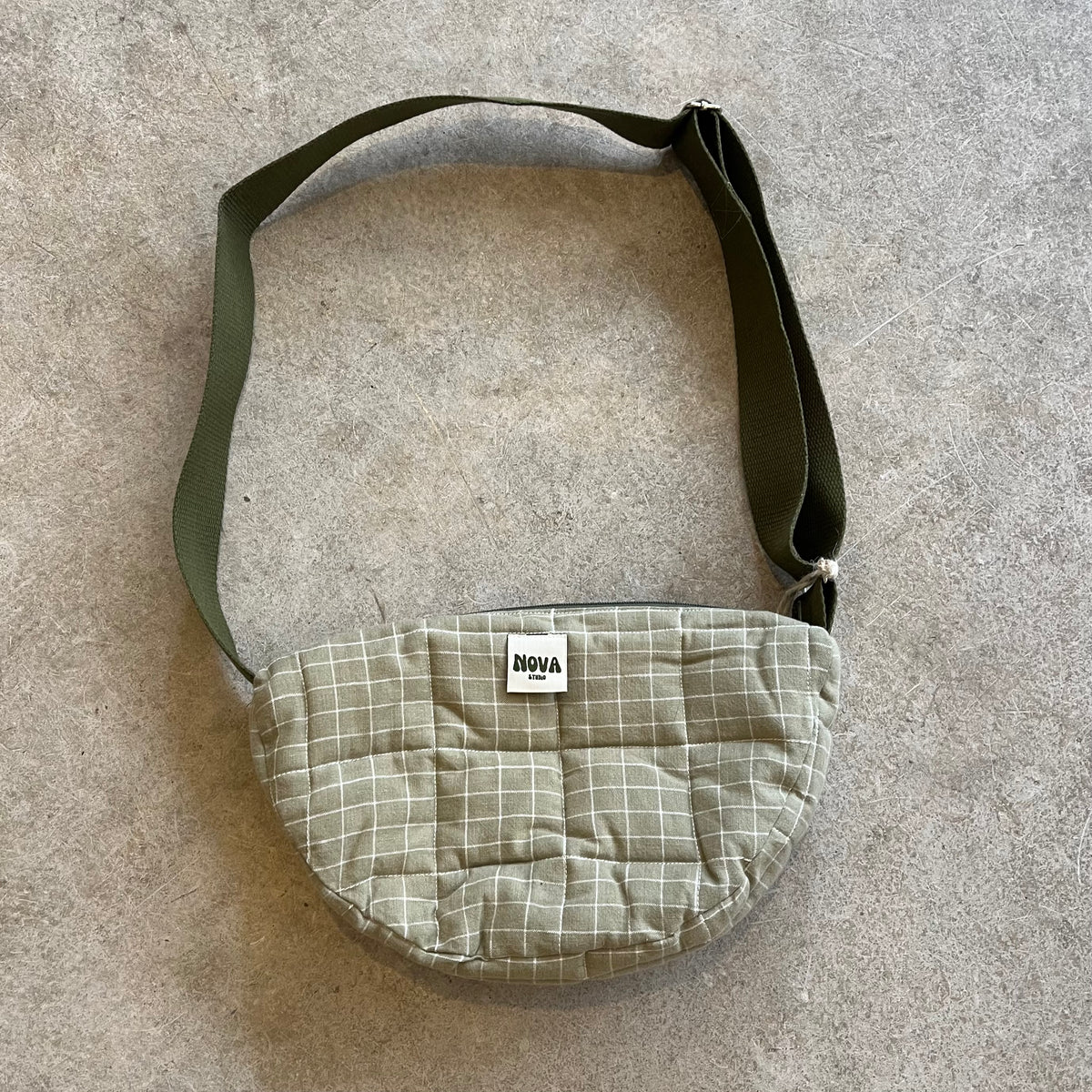 Khaki Check cotton padded cross body bag with adjustable strap and zip on grey concrete background