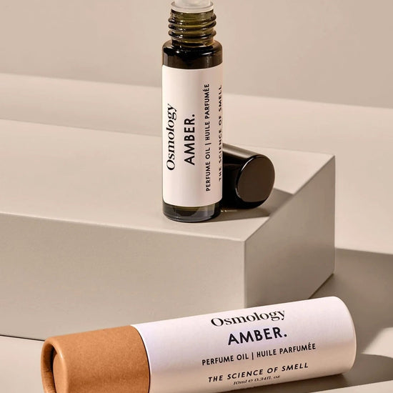 Osmology Amber perfume oil bottle and packaging on a neutral background