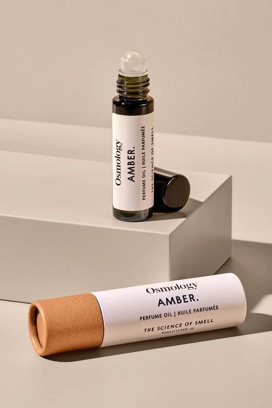 Osmology Amber perfume oil bottle and packaging on a neutral background