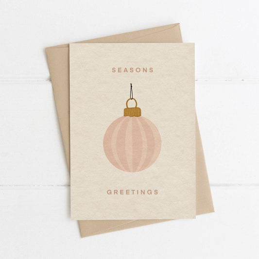 Greeting card with a pink ornament and 'Seasons Greetings' text on a beige background