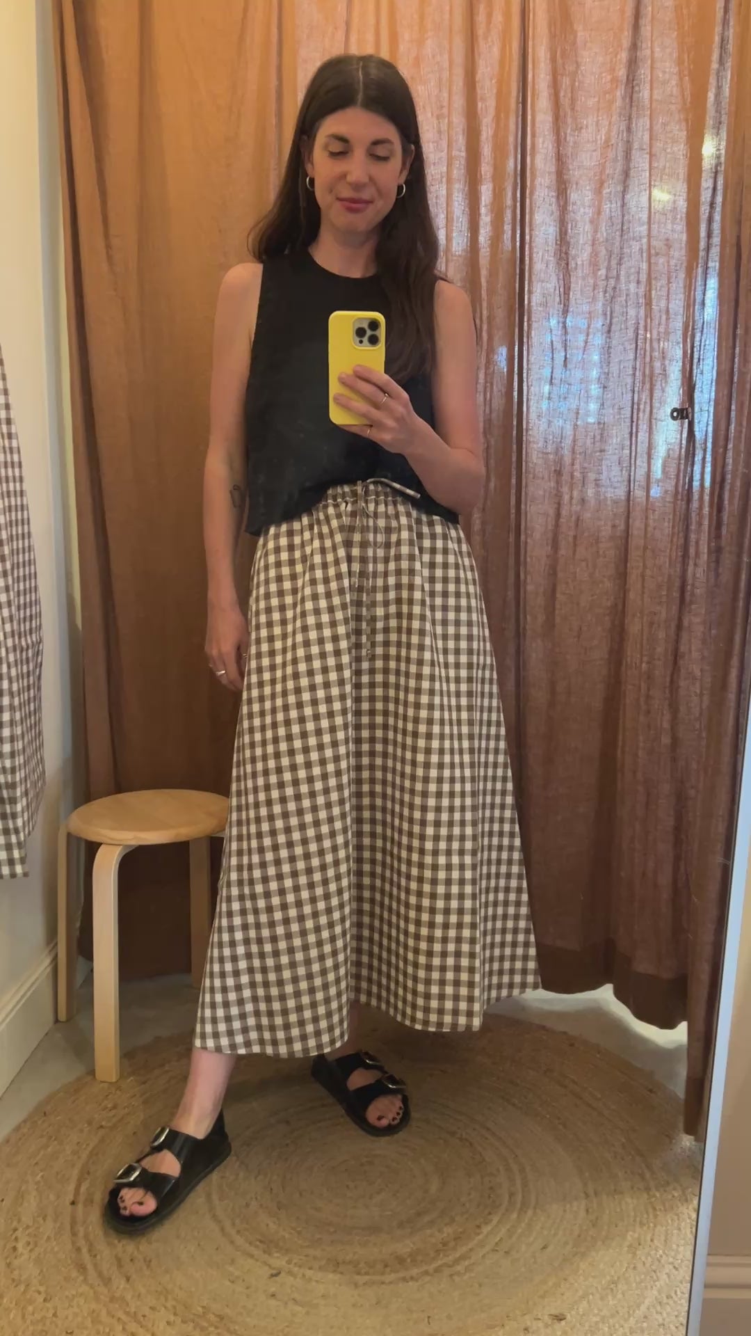 video showing model wearing brown gingham daily skirt and black top