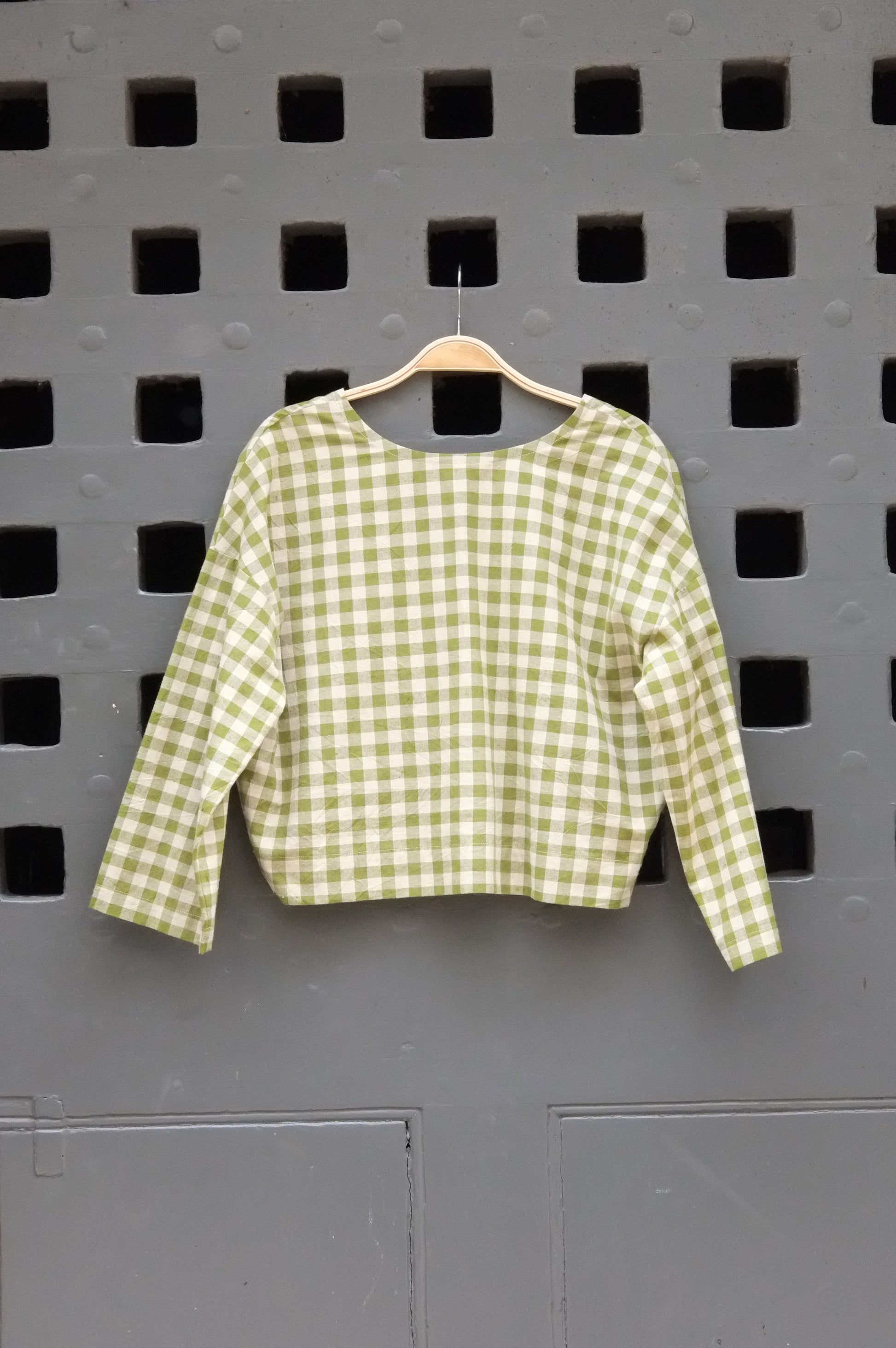 Green checkered shirt on a grey door background