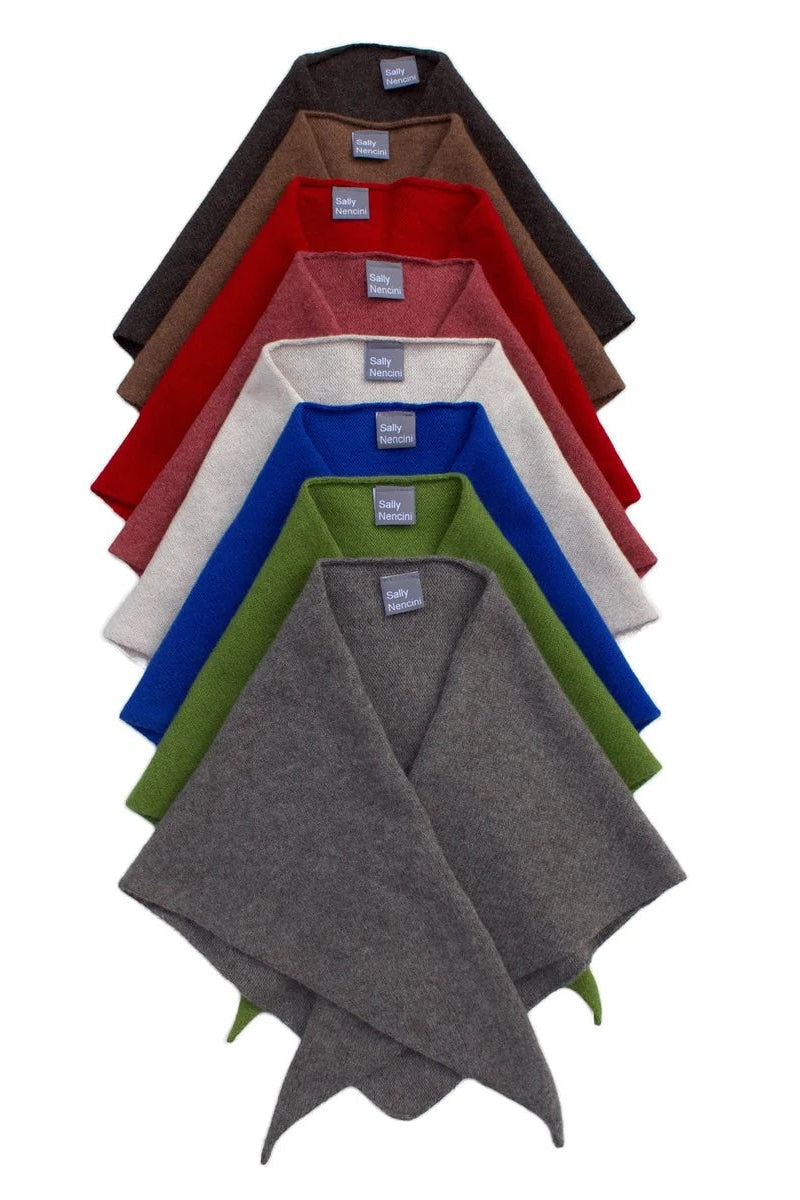 A stack of six folded knit poncho-style scarves in different colors, arranged vertically on a plain white background. The colors visible from top to bottom are dark brown, red, off-white, royal blue, olive green, and heather gray.
