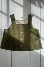 Load image into Gallery viewer, A khaki green ramie linen tank top with a square neckline, thick straps, and button-down front on a wooden background.
