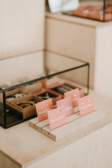 Jewelry display with pink name cards on a wooden surface