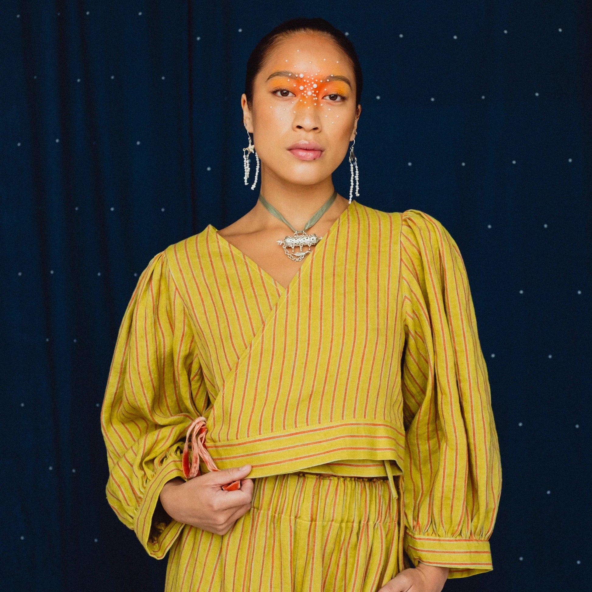 woman wearing a striped lime green wrap top on a navy blue background