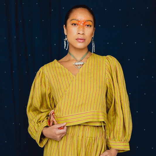 woman wearing a striped lime green wrap top on a navy blue background