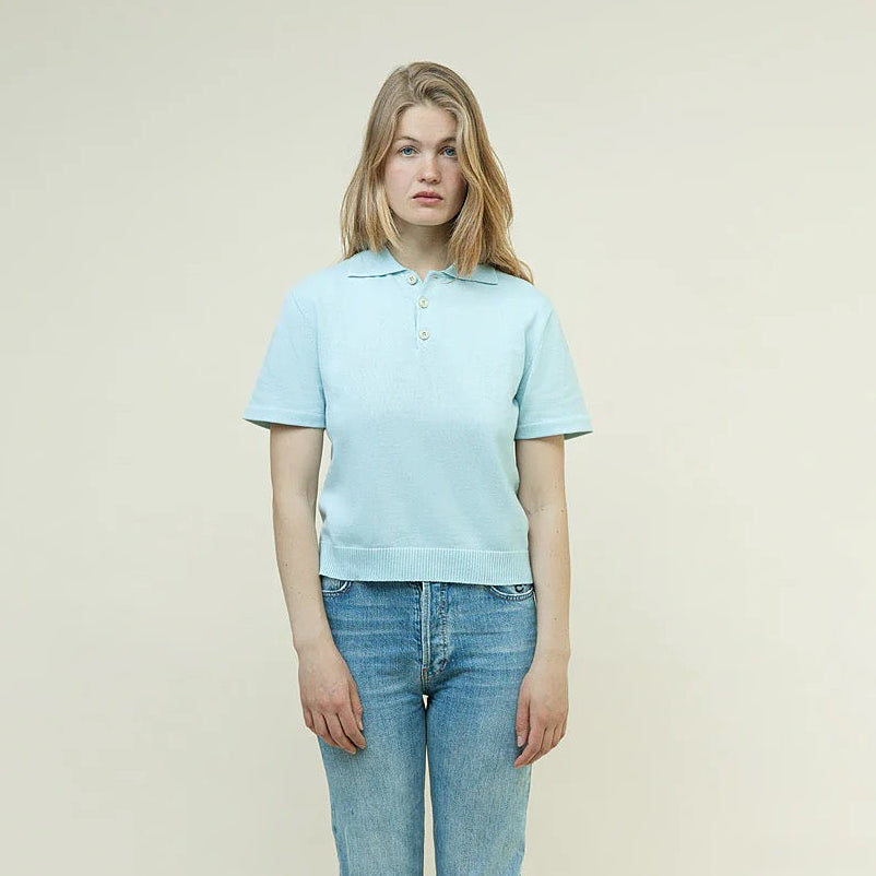 Person wearing a light blue polo shirt and jeans on a plain background