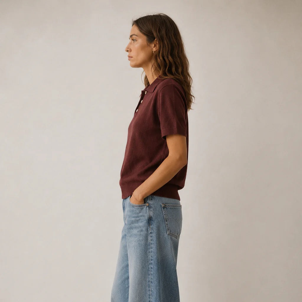 woman wearing brown polo shirt with long brown hair and blue jeans on white background