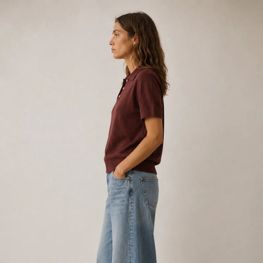 woman wearing brown polo shirt with long brown hair and blue jeans on white background