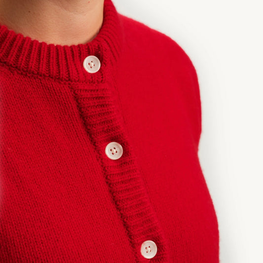 Close-up of a red knitted cardigan with white buttons on a white background