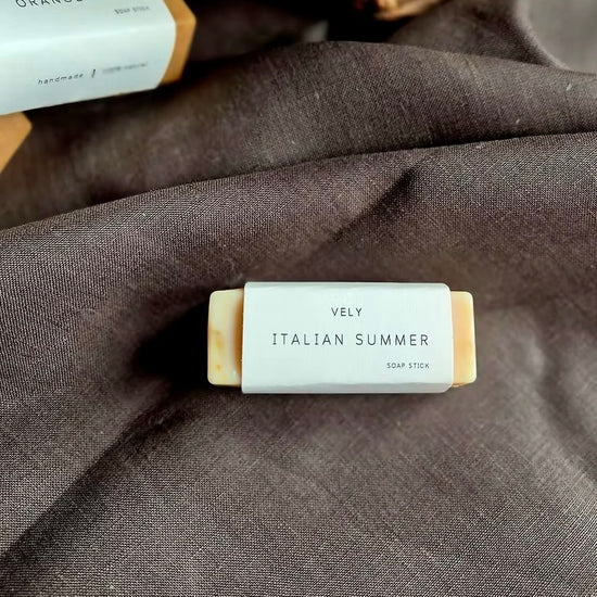 Bar of soap labeled 'Vely Italian Summer' on a dark fabric background