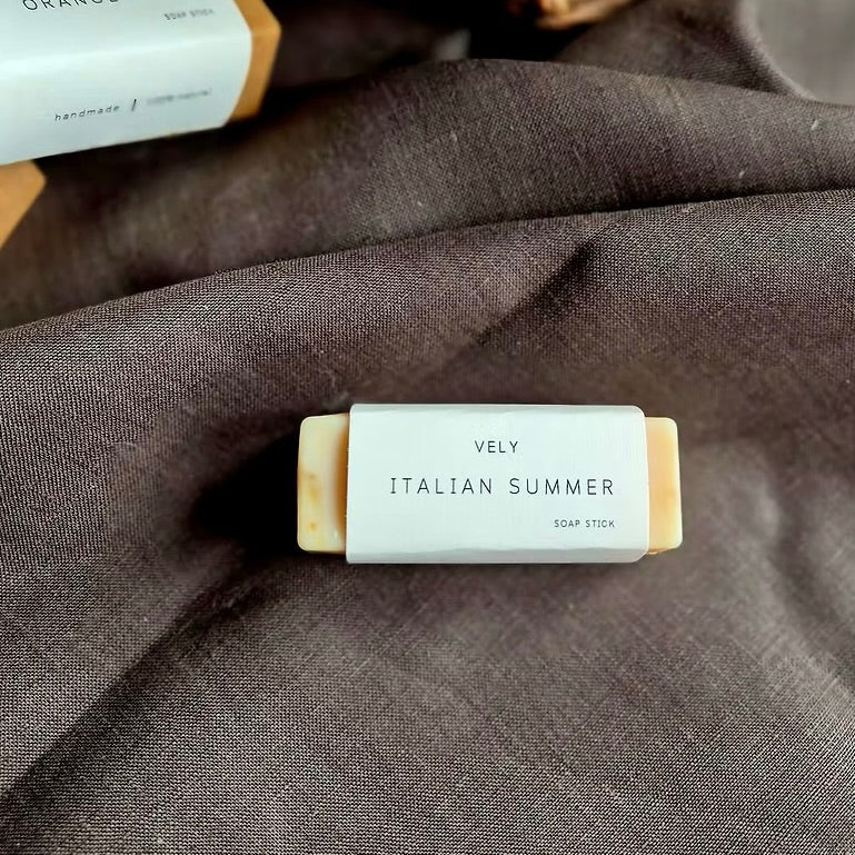 Bar of soap labeled 'Vely Italian Summer' on a dark fabric background