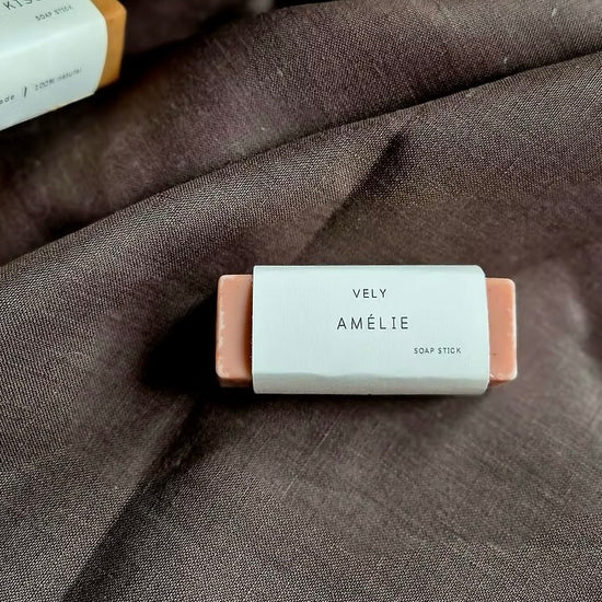 Soap stick with 'VELY AMELIE' branding on a textured fabric background