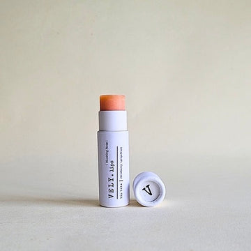 Lip Balm stick with a white casing and brown top on a light gray background
