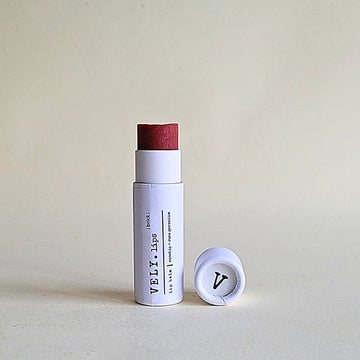 Lip balm with a white container and red cap on a light gray background