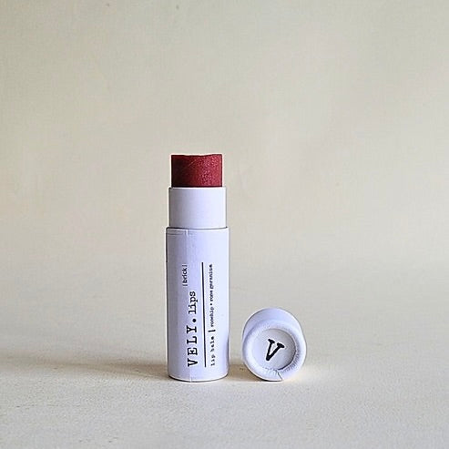 Lip balm with a white container and red cap on a light gray background