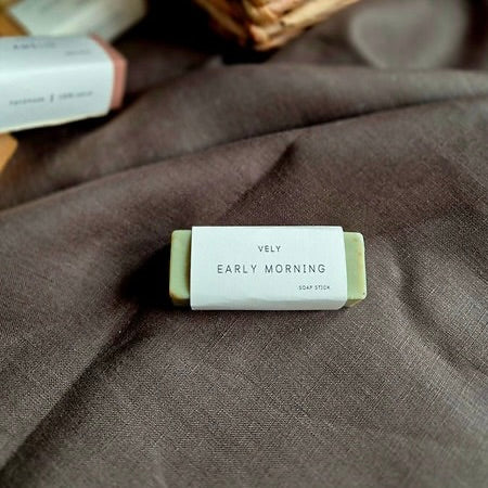 Bar of soap labeled 'Early Morning' by Vely on a textured fabric background