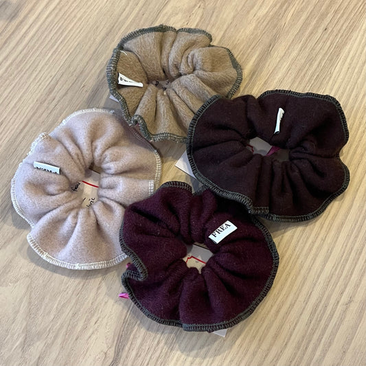 Four scrunchies in brown and purple on a wooden surface
