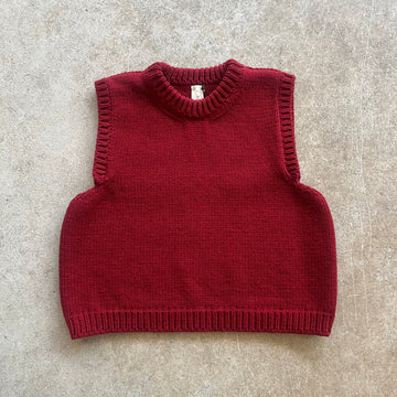 A red knitted vest on a beige background 