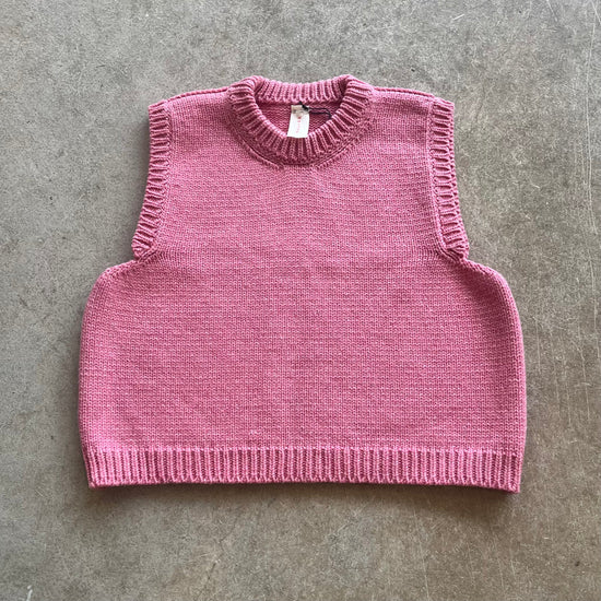 Pink knitted vest on a beige background 