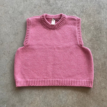 Pink knitted vest on a beige background 