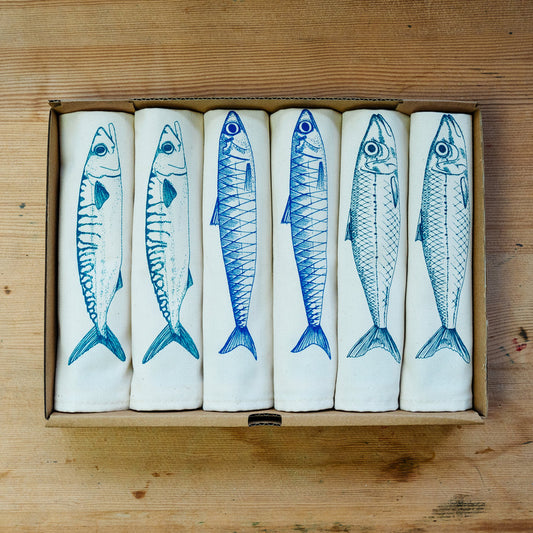 A set of white cotton napkins with blue fish prints, displayed in a giftbox.