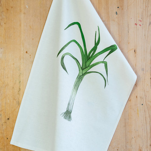 a leek illustrated tea towel on a wooden surface