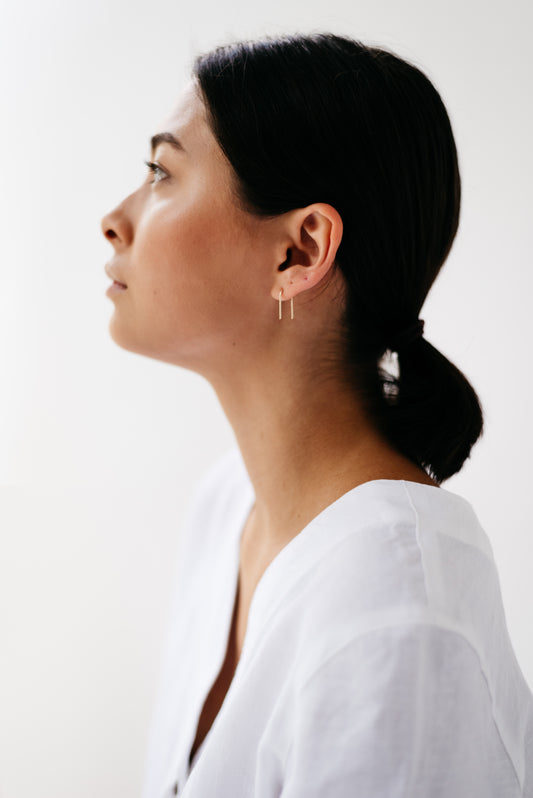 A pair of arch-shaped earrings made from Sterling silver and 9ct Gold on a model