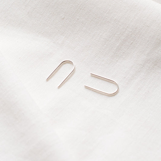 A pair of arch-shaped earrings made from Sterling silver and 9ct Gold, displayed against a light background.