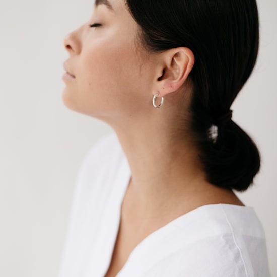 A model wearing a pair of Sterling Silver hoops